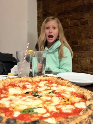 Karis astonished at the pizza in front of her.
