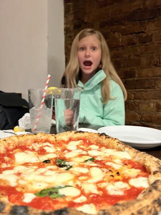 Karis astonished at the pizza in front of her.